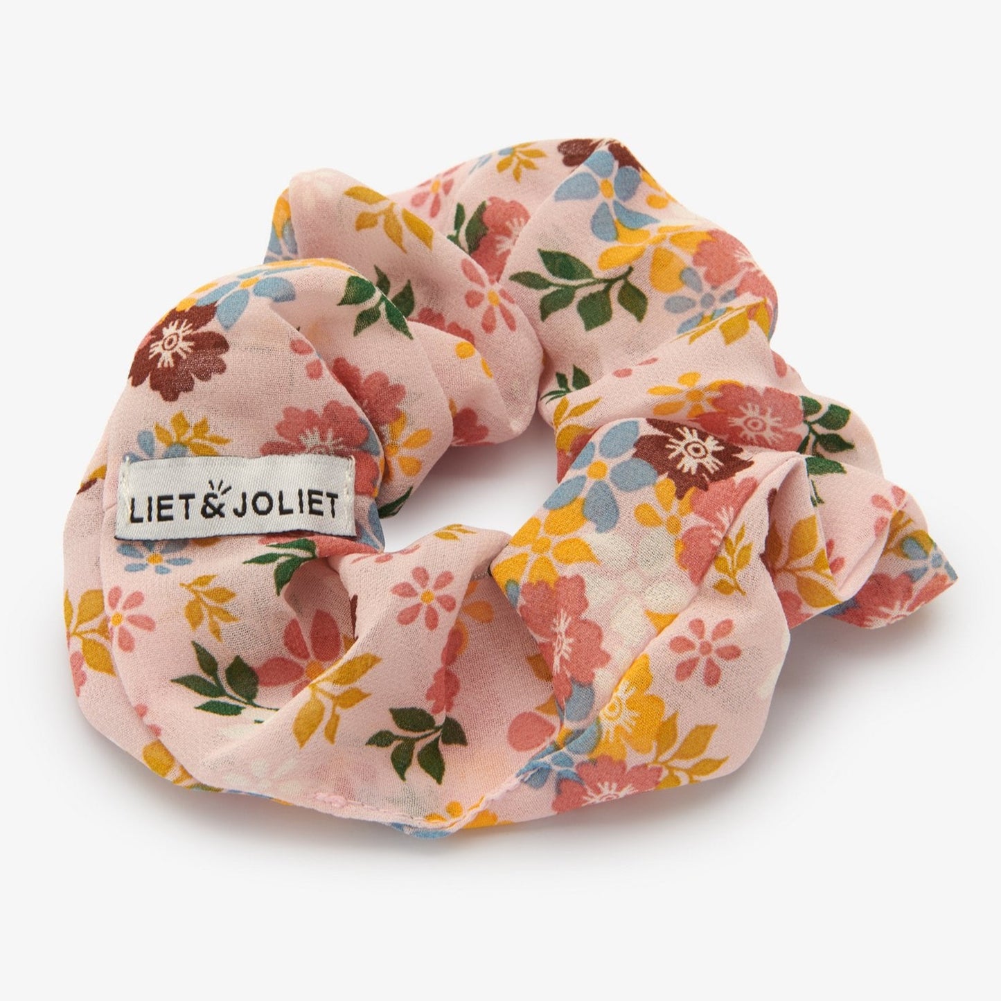 Voeg wat zomer toe aan je haar, met deze vrolijke scrunchie van Liet&Joliet.    De scrunchie is gemaakt van polyester en heeft een diameter van ongeveer 13cm. De stof heeft een mesh effect in een beige kleur met gekleurde bloementjkes.